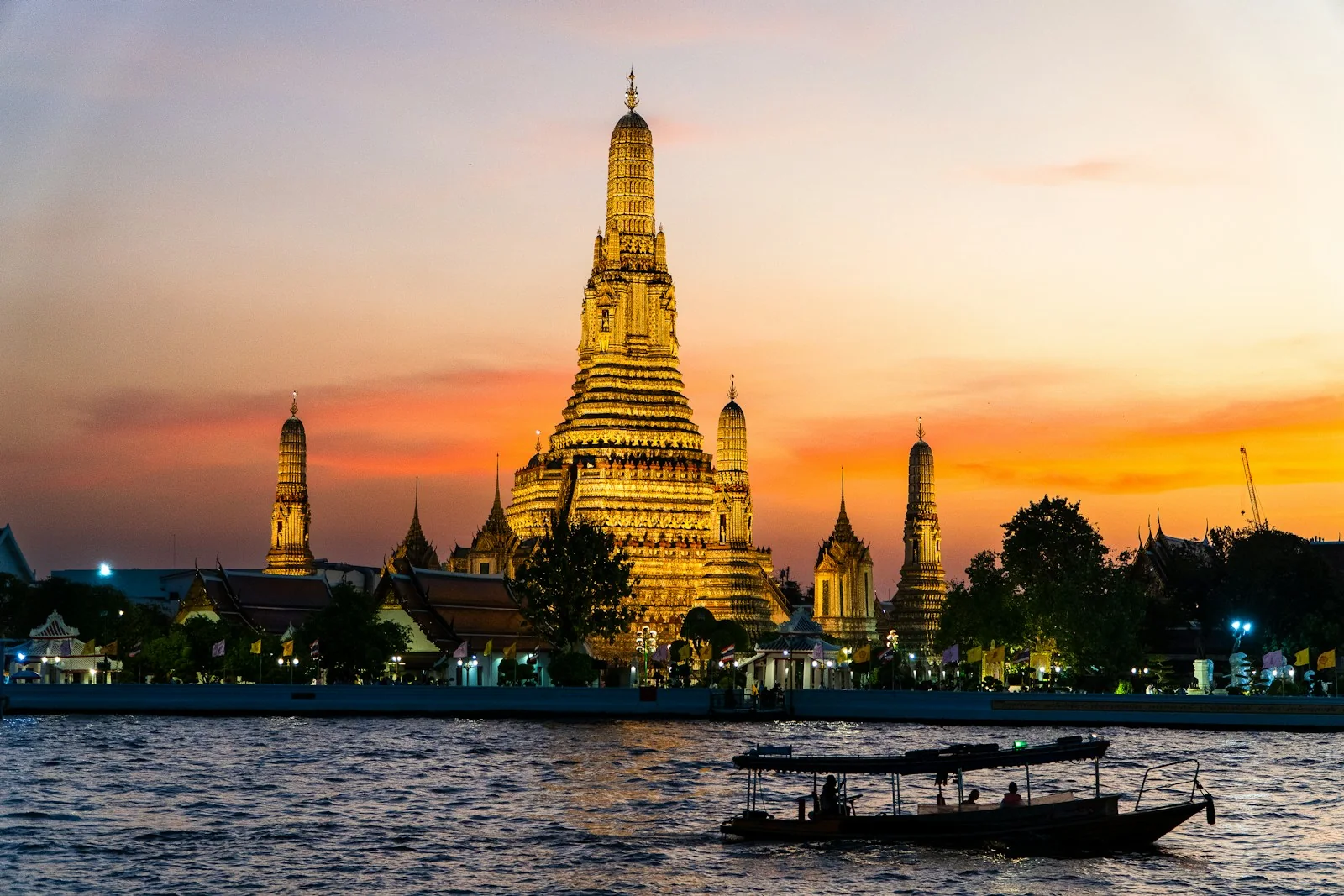 Wat Arun illuminato al tramonto sulle rive del Chao Phraya a Bangkok